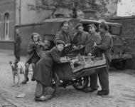 Corporal A. McLean and Sappers J.H.D. Pratte and P.E. Rivet, all of the Royal Canadian Engineers (R.C.E.), purchasing grapes from a Belgian with a dog-drawn cart, Bockhoute, Belgium, 20 October 1944 October 20, 1944.