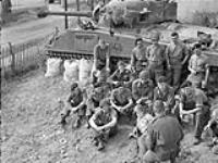Sergeant E. Owen (foreground) conducting an Orders (O) Ggroup for personnel of No.1 Protective Troop, Headquarters Squadron, 4th Canadian Armoured Brigade, Vaucelles, France, 7 August 1944 August 7, 1944.