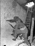 Riflemen D.H. Holmes and W.J. Wilkinson, both of The Regina Rifle Regiment, firing through loopholes in the wall of a captured barrack building, Vaucelles, France, 23 July 1943 July 23, 1944.