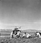 Inuit move out of the way as the helicopter of the Canadian Government Ship C.D. Howe lands at Pond Inlet July 1951.