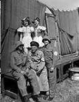 Ptes. Vera Cartwright and Enid Powell lend contrast to the Nazi costumes of Sgt. Frank Shuster, Sgt. Johnny Wayne all of Toronto, Ont. and Captain Ralph Wickberg of Winnipeg, Man. at Canadian Army 30-Jul-44