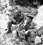 Regimental Sergeant-Major Antonio Lamontagne and Captain Pierre LaBrecque, both of Le Régiment de la Chaudière, sitting outside a church destroyed by shellfire, Carpiquet, France, 6 July 1944 July 6, 1944.