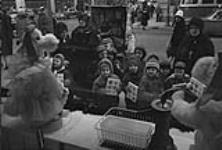 Enfants accompagnés de religieuses admirant une vitrine de magasin durant la période de Noël décembre 1961