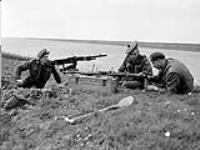 Personnel of the Highland Light Infantry examining abandoned German machine gun near the Afsluitdijk across the Zuiderzee. (Left to right): Pte. M. Upper, Cpl. W.J. Lutz, Pte. F.W. Gibson 19 Arp. 1945