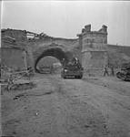 Vehicles of the 49th Division rolling under a railroad bridge in the attack on Arnhem 13 Apr. 1945