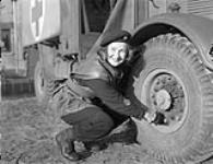 St. John's Ambulance driver Salley MacKean checking tire pressure on her ambulance, De Haan, Belgium, 4 February 1945 February 4, 1945.