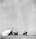 Cowhand leaving camp to herd cattle to summer pastures across the Milk River Mar. 1944