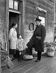 An unidentified officer of the Royal Canadian Naval Volunteer Reserve (R.C.N.V.R.) talking with a Japanese-Canadian family during the internment of fishing boats, British Columbia, Canada, 10 December 1941 December 10, 1941.