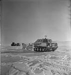 A Penguin snowmobile hauling 2 sleds - Operation Musk-Ox: testing army and Air Force equipment in the North Pole Apr. 1946