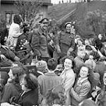 Des soldats d'Infanterie du West Nova Scotia Regiment, sur un porteur universel en route pour Rotterdam, sont entourés de civils hollandais qui célèbrent la libération des Pays-Bas May 9, 1945.