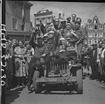 Dutch civilians celebrate Liberation by crowding on jeep of 1st Canadian Corps. Sgt. Doug Skene and Tpr. Frank Grummett somewhere in jeep 10 May 1945