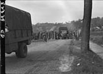 More empty trucks returning through barriers with two German guards checking returning vehicles 5 May 1945