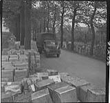Canadian trucks loaded with food for the Dutch population being driven to a distribution point along the Wageningan-Rhennan highway after the food distribution agreement with the Germans. Cases of food line the highway 3 May 1945