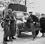 German soldiers guarding food dump established in forward area, talking to one of the Dutch drivers who is to distribute the food in a Canadian truck 3 mai 1945