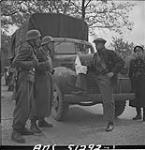 German soldiers guarding food dump established in forward area, talking to one of the Dutch drivers who is to distribute the food in a Canadian truck 3 May 1945