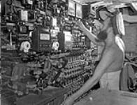 Leading Seaman Reg Libby working in the low power room of the cruiser H.M.C.S. UGANDA, which is serving with the British Pacific Fleet, 6 August 1945 August 6, 1945.