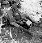 War correspondent Ross Munro of the Canadian Press typing a story in the battle area between Valguarnera and Leonforte, Italy, August 1943 August 1943.