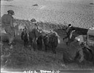 Comrades carry wounded member of North Shores down dyke after being evacuated by alligator, Scheldt pocket embarkation point, west of Terneuzen 13 Ot. 1944