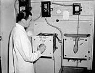 An unidentified staff member of the Royal Canadian Navy Medical Research Unit setting the electric motor which operates the seasickness machine, Montreal Neurological Institute, Montreal, Quèbec, Canada, November 1943 November 1943.
