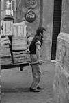 Worker pulling a cart of wooden boxes. Rome, Italy, 1965 1965