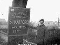 Regimental Quartermaster-Sergeant W.J. Hansford of The Perth Regiment pointing to a sign which reads "You Are Now Entering Stratford". Sneek, Netherlands, 22 November 1945 November 22, 1945.