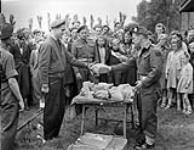 Lieutenant-Colonel R.B. Somerville of The Cape Breton Highlanders presenting the first prize to Captain J.M. Lockington, winner of the running broad jump event, Track and Field Day, Sneek, Netherlands, 3 July 1945 July 3, 1945.