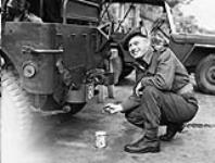 An unidentified officer of The Lorne Scots (Peel, Dufferin and Halton Regiment) stencilling the regiment's identification number on a jeep, England, ca. 30 May-1 June 1943 [ca. May 30 - June 1, 1943].