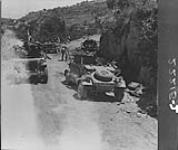 Allied jeeps passing burnt-out German vehicles 23-28 Oct. 1943