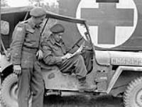 H/Captain J.L. Steele, Chaplain of The Royal Winnipeg Rifles, talking with his driver, Rifleman J.L. Simard, France, 16 July 1944 July 16, 1944.