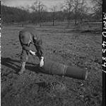 Capt. R.F. Davey, Black Watch 'B' Company, examining an unexploded front line rocket used by the Germans. Groesbeek, Netherlands, 3 Feb. 1945 3 FEB. 1945
