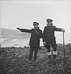 Royal Canadian Mounted Police (R.C.M.P.) constables Ed Jones (left) and Fred Stiles who will be stationed at Twin Glacier - look over the valley for a suitable building site Aug. 1953