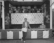 Gaming booth and operator at fair. Oshawa, Ontario, July 1982 JULY 1982