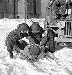 Privates Arthur Richard and Aurele Nantel of the Regimental Aid Party, Le Régiment de Maisonneuve, treating a wounded soldier near the Maas River, Cuyk, Netherlands, 23 January 1945 January 23, 1945.