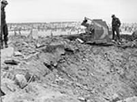 Lieutenant-Colonel D.G. Crofton, Commanding Officer of the 1st Battalion, The Canadian Scottish Regiment, examining the wreckage of a German 155mm. gun, Breskens, Netherlands, 28 October 1944 October 28, 1944.