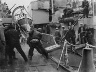Personnel du USS BUCK transférant des munitions de quatre pouces au NCSM HAIDA, durant une patrouille au large de la côte est de la Corée 9 June 1953