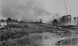 View looking west from east wall of Abasand Oils Ltd., quarry. Ruins of separation plant loading platform, machine shop and separation plant are obscured by the smoke. McMurray (vic.), Alberta, 16 June 1945 16 June 1945