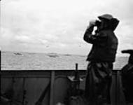 Lookout on the flagdeck of H.M.C.S. PRINCE DAVID watching assault craft heading ashore to the Normandy beachhead, France, 6 June 1944 June 6, 1944.