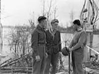 Deux hommes de la résistance hollandaise discutent avec le Sapeur A.T. White de la 3e division d'ingénieurs près de la frontière belge