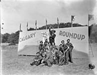 Entertainers and troopers of The Calgary Regiment in front of a sign reading "Calgary Roundup", an event which included sports, entertainment, refreshments, and the presentation of a silver service to the regiment's commanding officer, Apeldoorn, Netherlands, 18 June 1945 June 18, 1945.