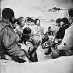 Inuits rassemblés à l'intérieur d'un igloo pour le repas (Photo tirée du film de l'Office national du film intitulé " Land of the Long Day " ) 1952