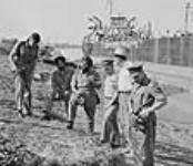 Membres canadiens du groupe de la Commission internationale chargé de la surveillance de la trêve en Indochine discutant de l'inspection d'un ravitailleur en munitions 1955