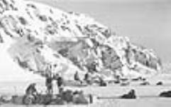 [Noah Avadluk (en bas à gauche), guide de la Gendarmerie royale du Canada (GRC), et des agents de la GRC.] 1949-1950