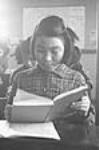 Inuit girl reading from a schoolbook in a classroom, Inukjuak (formerly Port Harrison), Quebec 1947-1948.