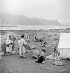 Domestic activity in Inuit camp. C.D. HOWE at the back [Woman on the far left is Avuniq.] July 1951