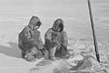 Two unidentified Inuit by a fishing hole 1949-1950