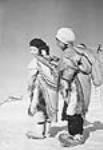 [(Left to right): Mary Hickes (Tusayi's daughter) and Otuqayuaq playing outside. Mary is carrying a baby doll on her back.] 1949-1950