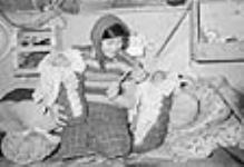 Cree woman [Emma Visitor-Atsynia] in her home with two babies 1947-1948.