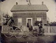 Unidentified man and women in front of a house ca. 1870