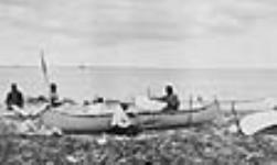 [Innu men constructing canoes at North West River]. Original title: A group of Innu making their canoes at the North West River in Labrador ca. 1920