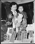 Mrs. Kwok Sun Louie, who came to Canada from Hong Kong in 1954, shopping with daughter Lorraine, 6, for delicacies to be used in preparing the traditional foods for Chinese New Year c.a. 1962